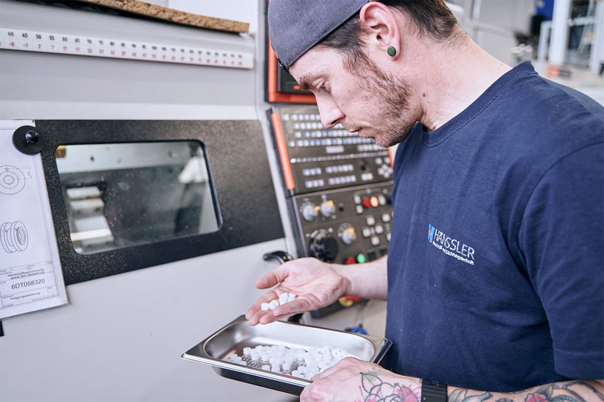 Ein Mitarbeiter prüft produzierte Kolben aus dem Werkstoff POM
