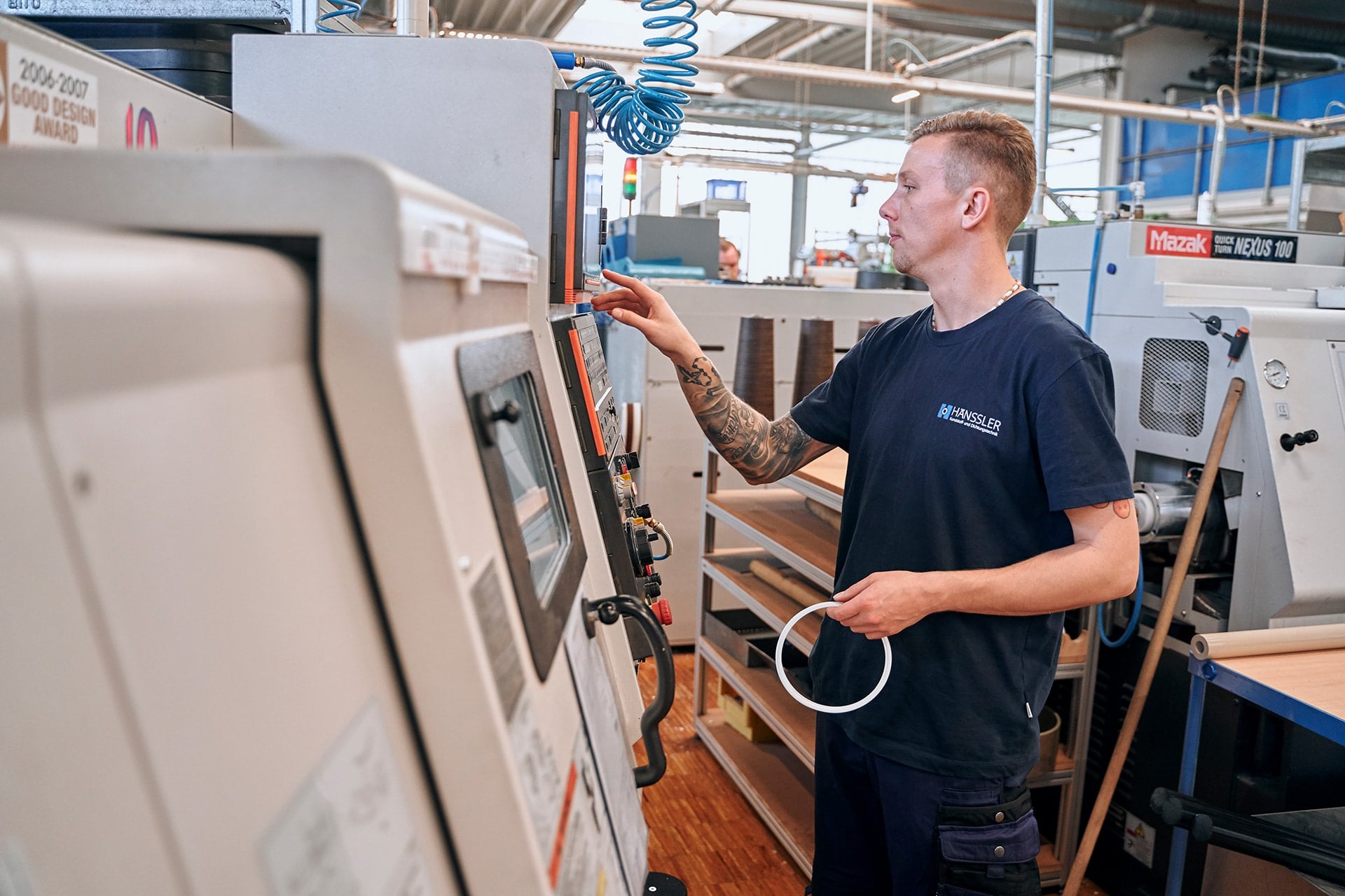 Ein Mitarbeiter hält einen Dichtring in der Hand und bedient eine Maschine