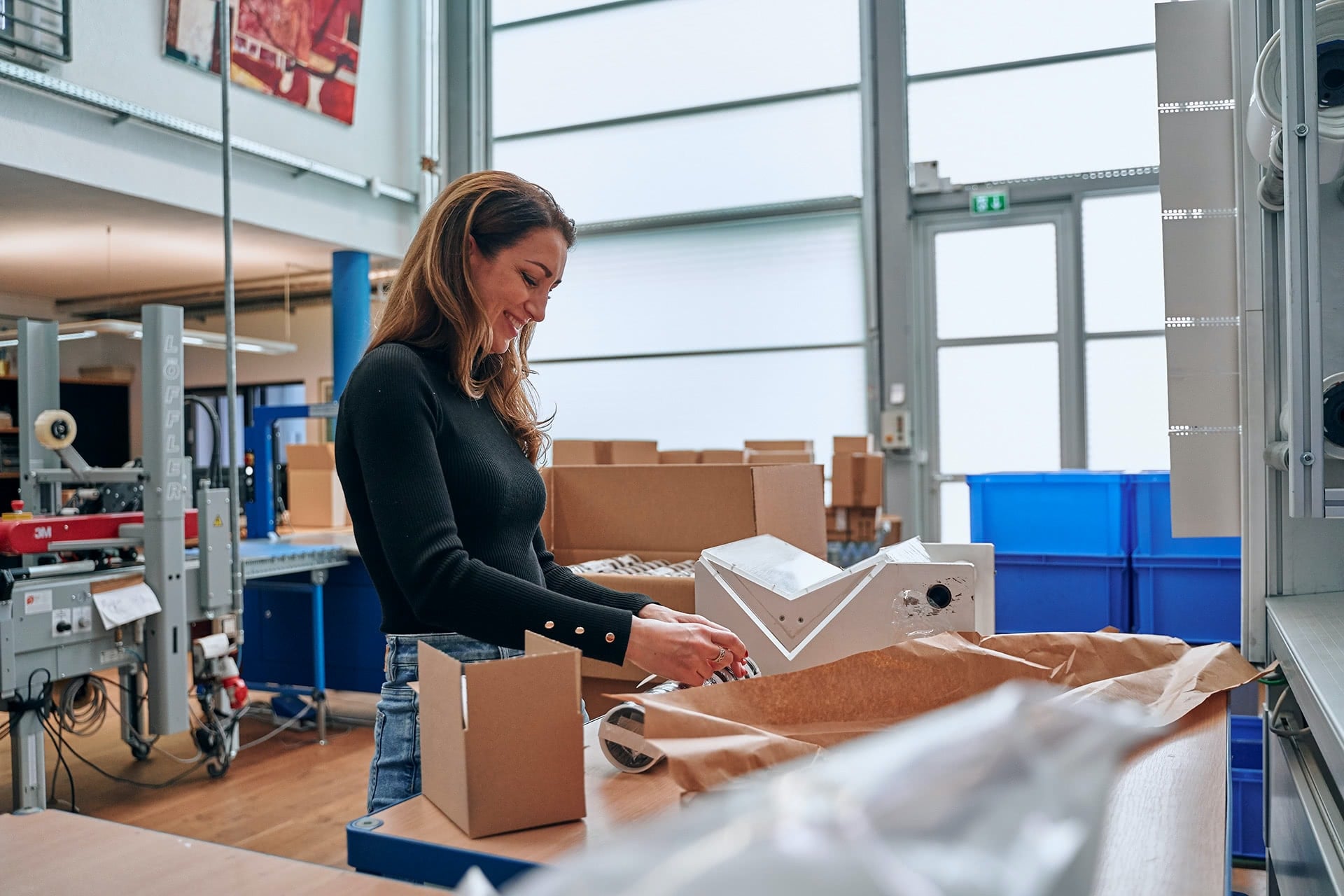 Eine Mitarbeiterin verpackt Teile für den Versand