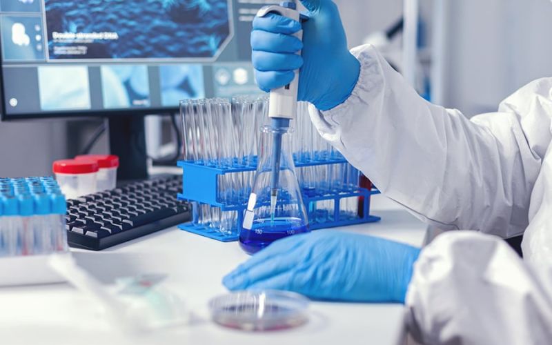 A laboratory in which an employee wearing gloves is currently aspirating liquid with a pipette