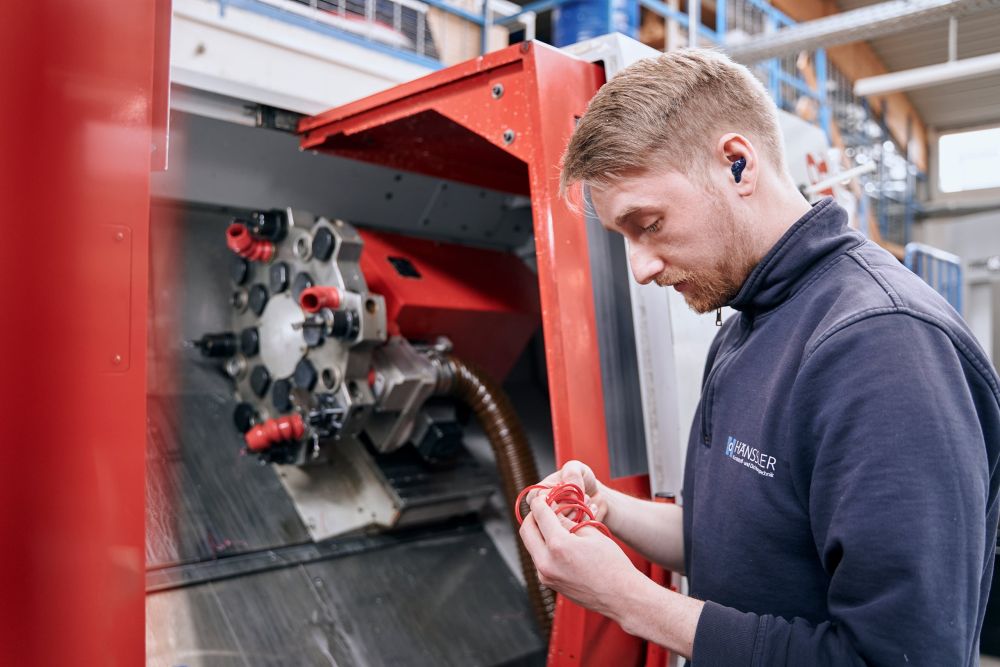 Employee stands in front of milling machine and checks part